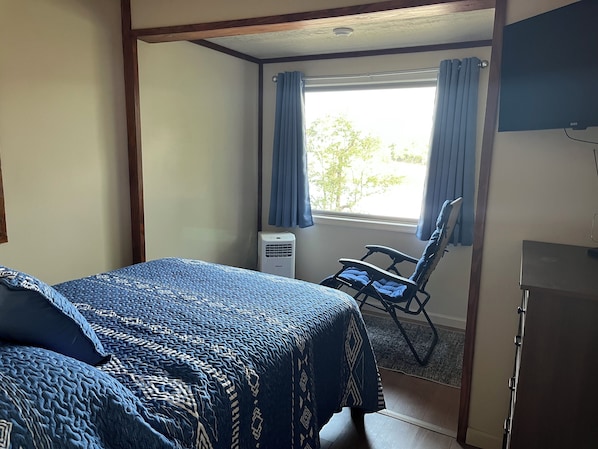 Una habitación con una cama, una silla, un escritorio y una ventana con cortinas.