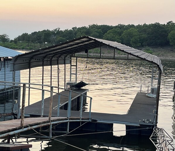 Un muelle techado con barandilla metálica y plataforma de madera que se extiende sobre el agua.