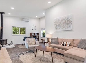 Ein modernes Wohnzimmer mit Sofa, Sesseln, Couchtisch und Kamin.