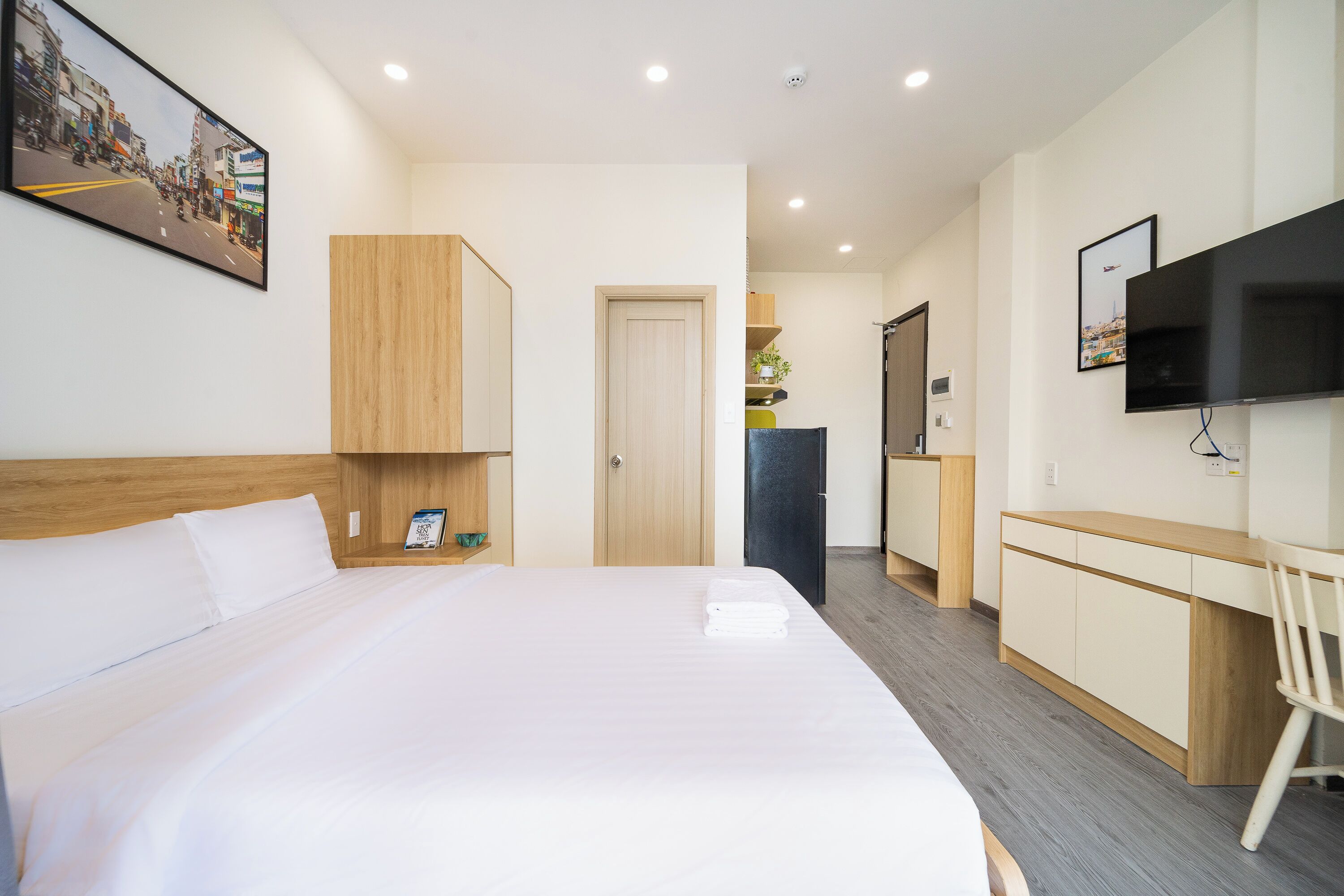A hotel room with a large bed, a desk, a television, and a door leading to a bathroom.