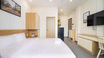A hotel room with a large bed, a desk, a television, and a door leading to a bathroom.