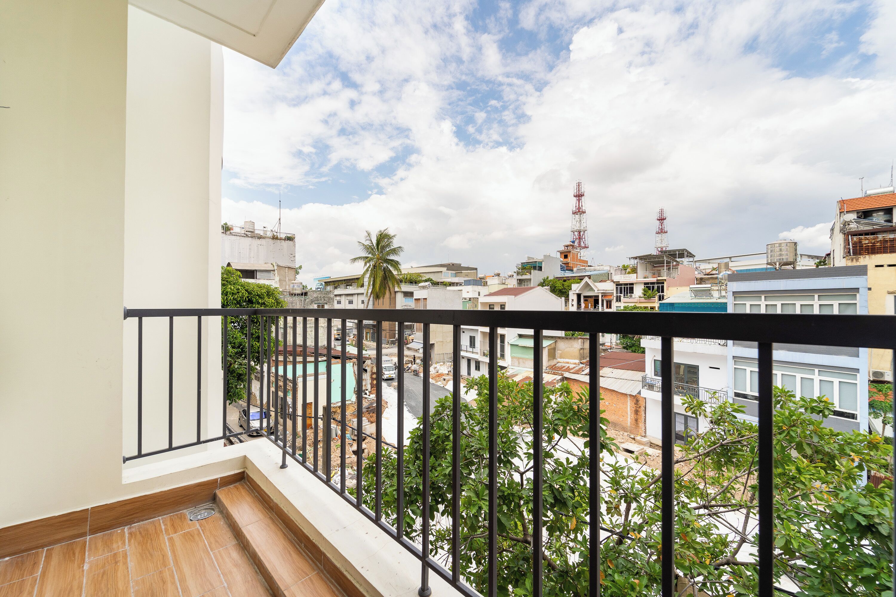 A balcony with a view of a cityscape, including buildings and a clear sky.