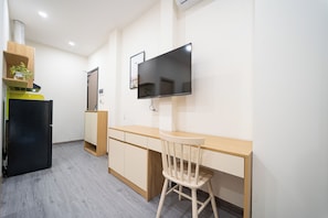 A modern kitchen with a built-in refrigerator, a wooden cabinet, a black countertop, and a wall-mounted TV. - YOURS HOMES - TAN SON NHAT T3 (Ho Chi Minh City)