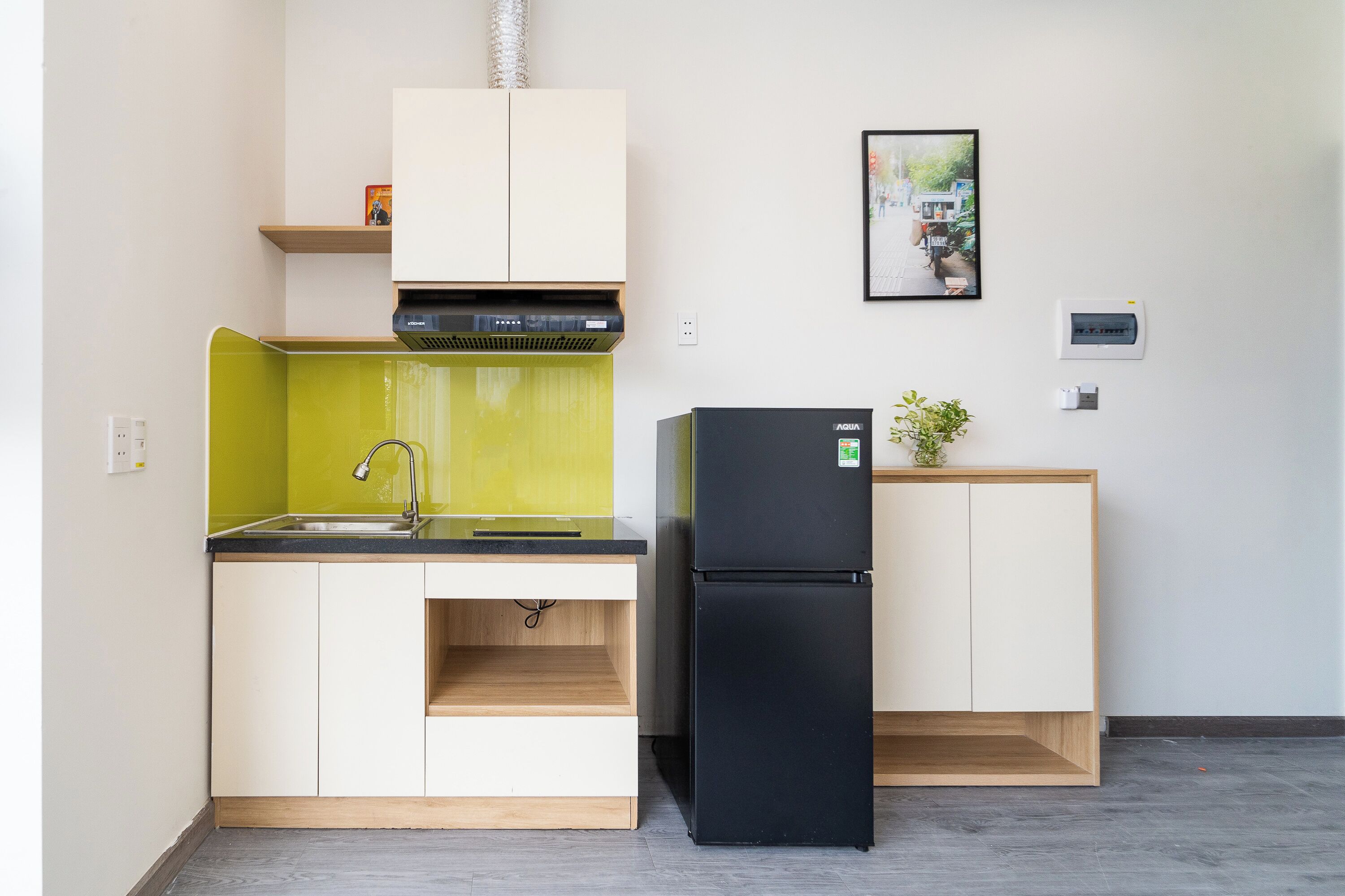 Cocina compacta con un lavamanos, un refrigerador negro y una pequeña encimera.