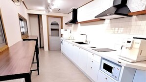 A modern kitchen with white cabinetry, a wooden dining table, and a built-in oven. - 4-min Walk Sinsa Station PRIVATE STUDIO #Gangnam #Central #Clinic #Treatment (Seoul)
