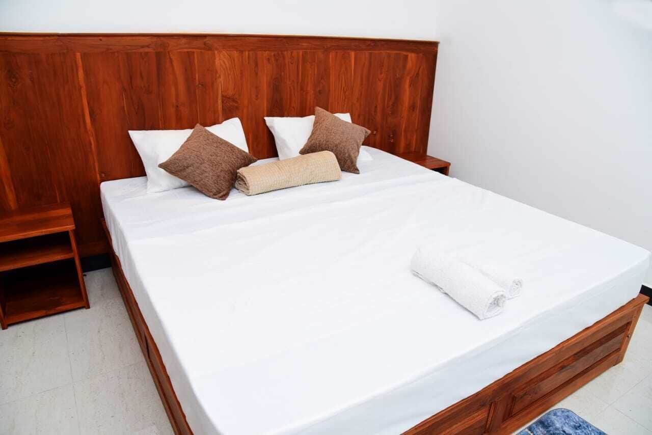 A bed with a wooden headboard, white bedding, and brown pillows.