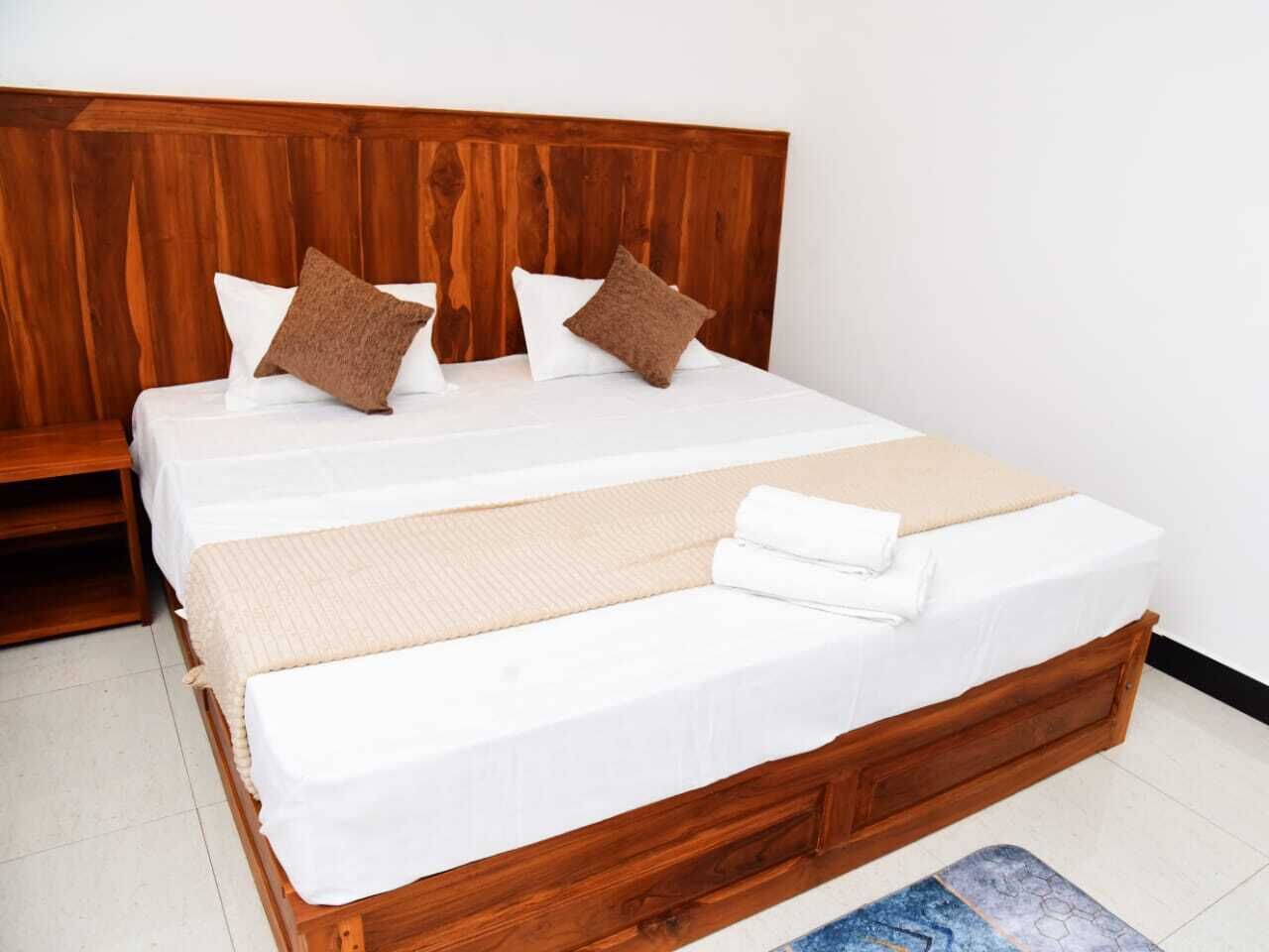A double bed with a wooden headboard, two pillows, and a folded blanket.