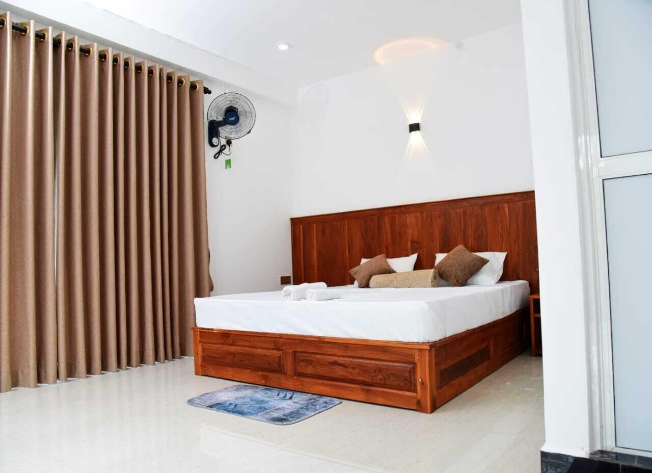 Une chambre avec un lit en bois, un ventilateur de plafond et une fenêtre avec des rideaux.