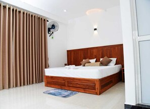 A bedroom with a wooden bed, a ceiling fan, and a window with curtains.