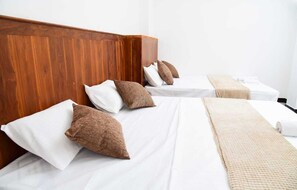 A hotel room with a wooden headboard, two beds with white linens, brown pillows, and a beige throw blanket. - Lovely Homestay  (Ella)