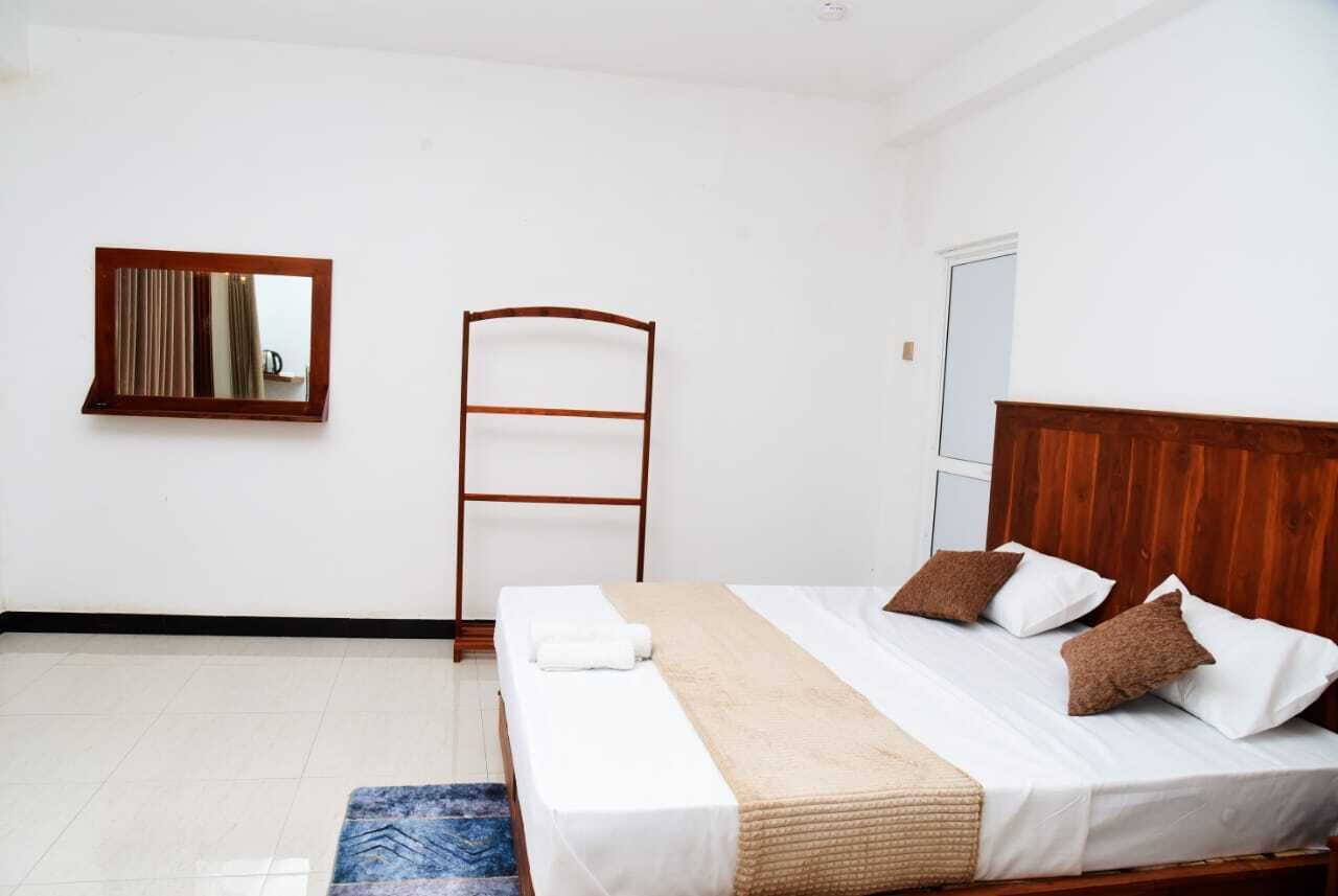 Une chambre à coucher avec un lit, une tête de lit en bois, un miroir et une fenêtre.