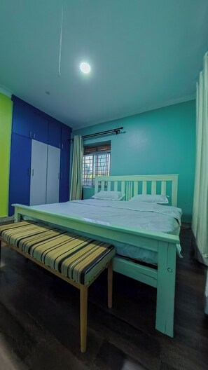 Ein Zimmer mit einem Bett, einer Sitzbank und einem Kleiderschrank.