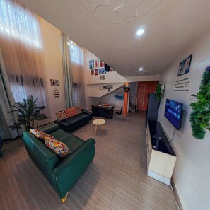Ein modernes Wohnzimmer mit einem grünen Sofa, einem kleinen runden Tisch und einem flachbildfernseher an der Wand.