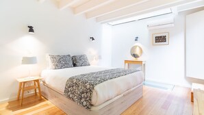 Una camera da letto moderna con un letto grande, lampade da comodino, un tavolino e uno specchio fissato alla parete.