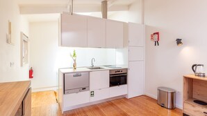 Una cucina compatta con mobili bianchi, un lavello in acciaio inossidabile e un forno integrato.