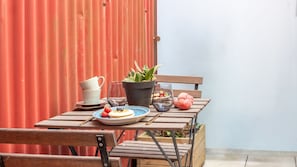 Una mesa de madera con un plato de comida, un vaso de agua, una jarrón y una planta en maceta.