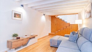 Un soggiorno moderno con una scala in legno, un divano, un tavolino da caffè e una mensola a parete.