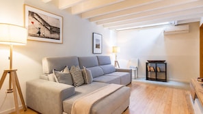 Una sala de estar moderna con un sofá, una lámpara de pie, una mesita auxiliar y una estantería.