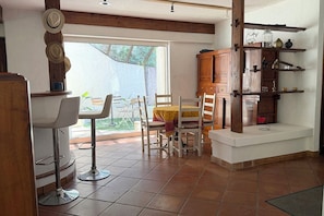 Ein Essbereich mit Tisch und Stühlen, ein Holzschrank mit Regalen und Blick durch ein Fenster.