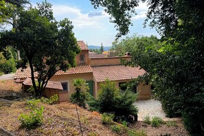A house with a tiled roof, surrounded by trees and a garden.
