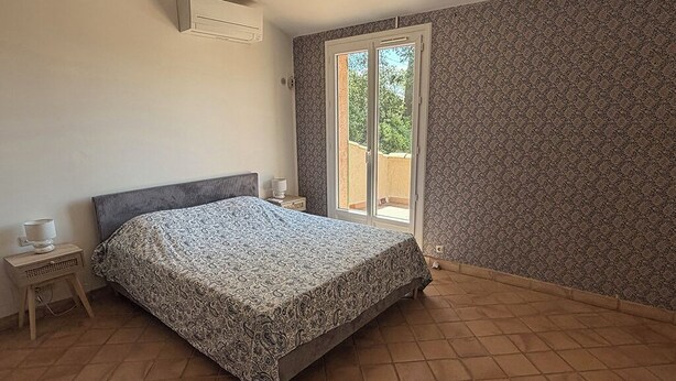 Ein Schlafzimmer mit einem Bett, einem Nachttisch, einem Fenster mit Blick und einer Wand mit Muster.