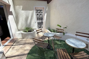 A patio area with outdoor seating, a door with a decorative gate, and potted plants.