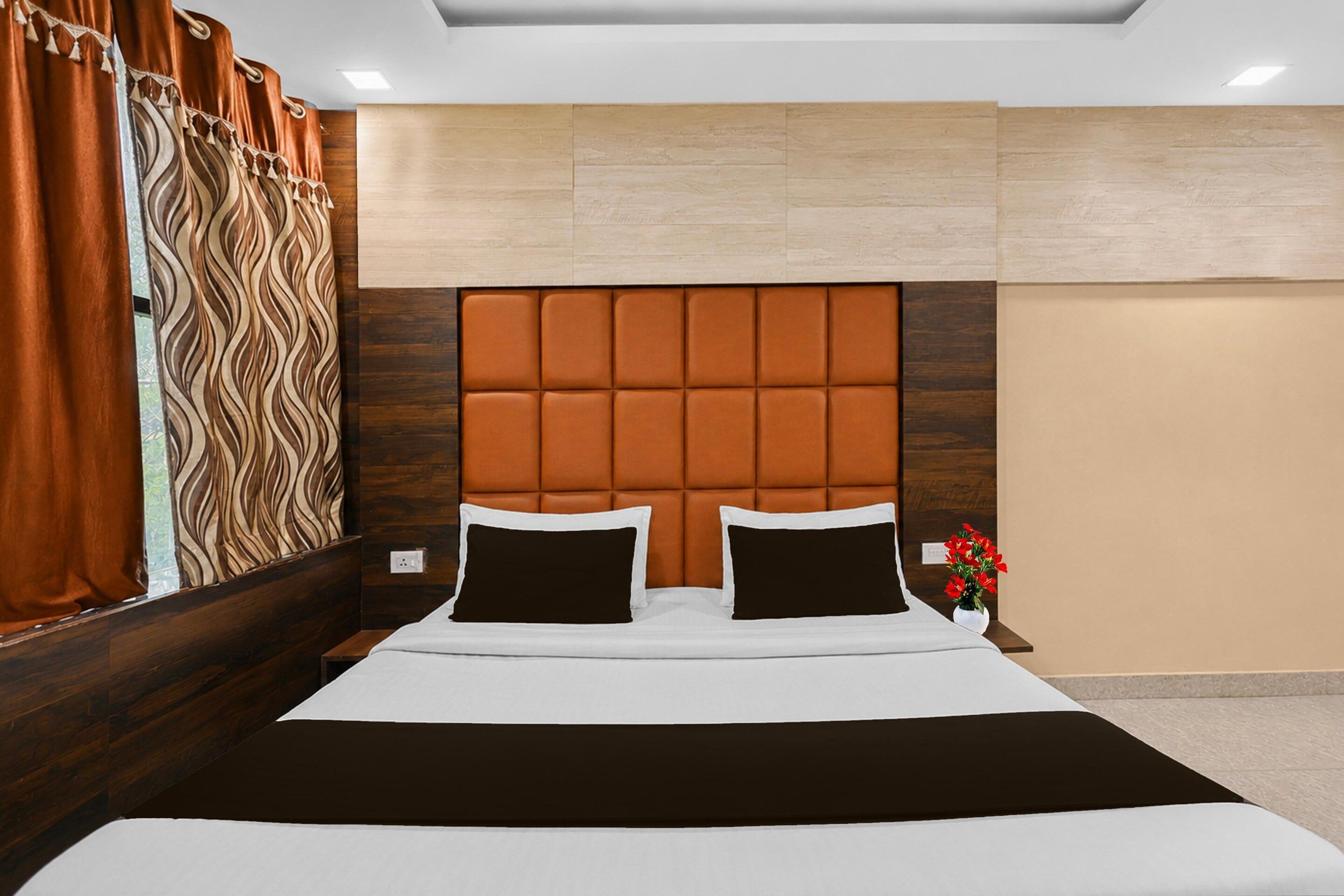 Una habitación de hotel con una cama grande, un cabecero de diseño acolchado y una ventana con cortinas.