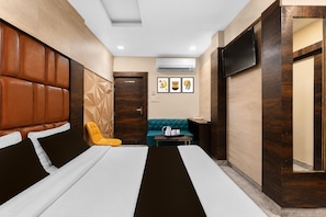 Una habitación de hotel con una cama grande, un sofá, una mesita y un televisor.