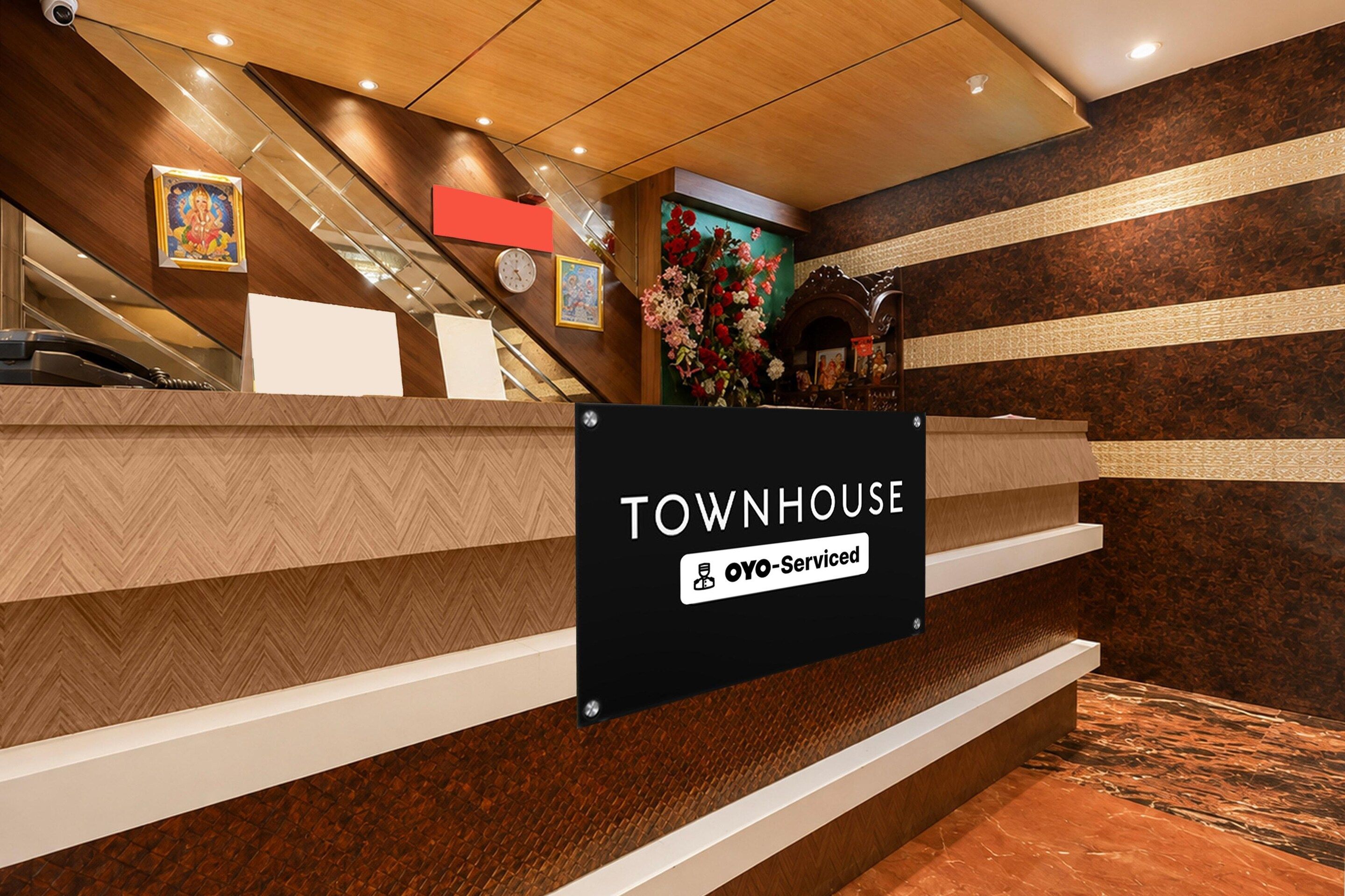 En receptionsdisk med en skylt som visar texten ”TOWNHOUSE” och ”OYO-Serviced”.
