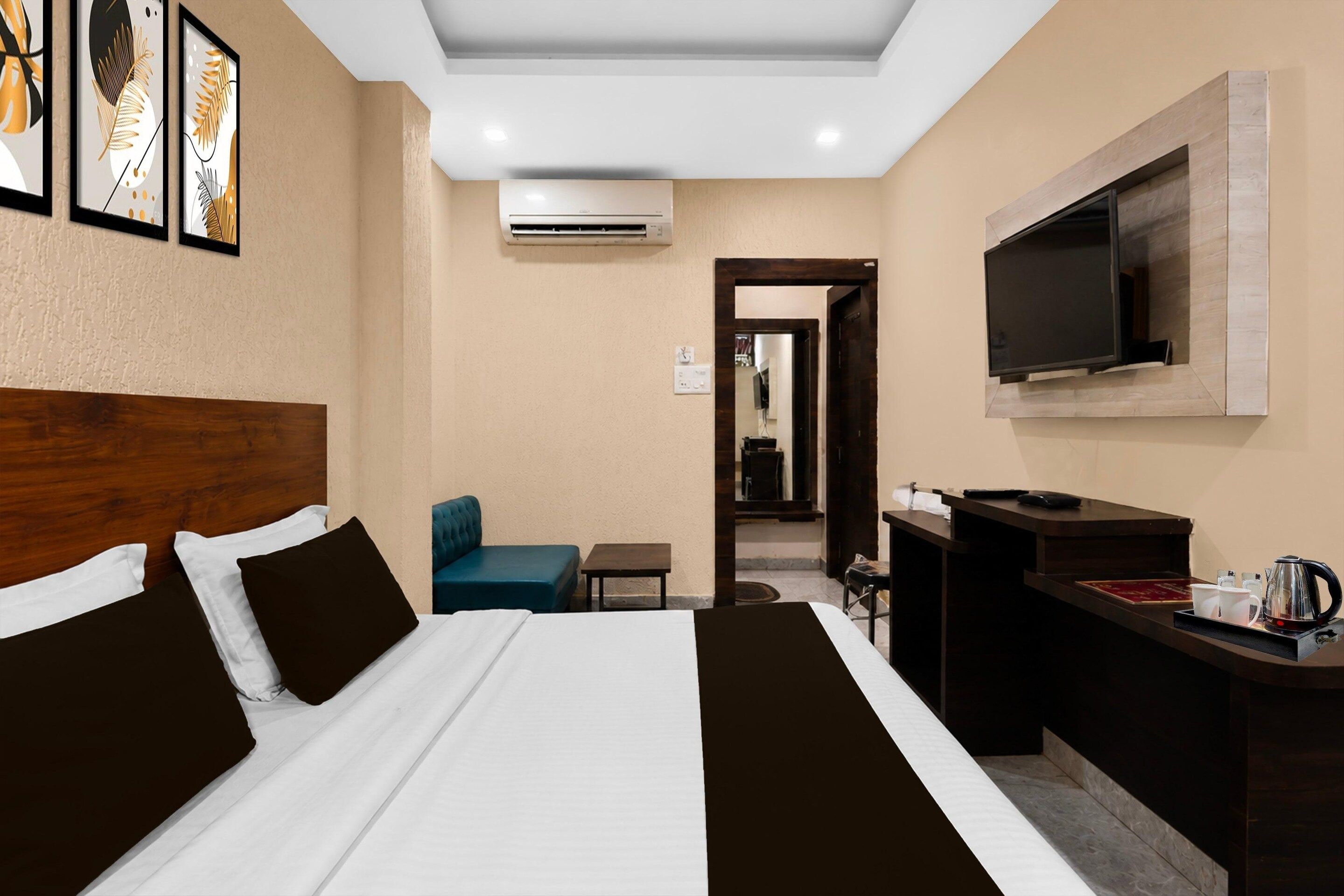 A hotel room with a bed, a desk, a chair, a television, and artwork on the wall.