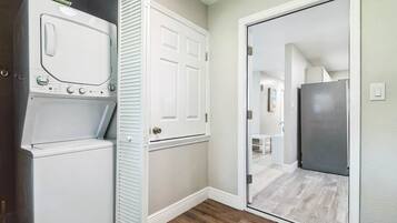 A laundry room with a washer, dryer, and a door leading to a hallway.