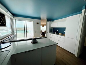 A modern kitchen with white cabinets, a large window, and a view of the sea. - Arcachon, luxury apartment, first-row ocean view (ARCACHON)