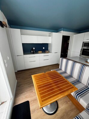 A modern kitchen with white cabinetry, a blue ceiling, and a striped sofa. - Arcachon, luxury apartment, first-row ocean view (ARCACHON)