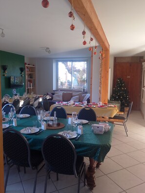 Ein Essbereich mit gedecktem Tisch, Stühlen, einem Weihnachtsbaum und Blick ins Freie.