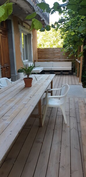 Eine Terrasse aus Holz mit Tisch, Stühlen, einem Blumentopf und einer Bank.