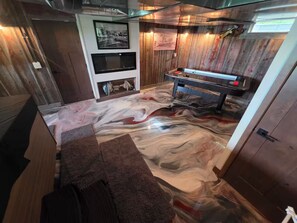 A room with a marble floor, a pool table, and wooden paneling.