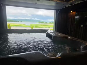 A hot tub with a view of a lake and green fields.