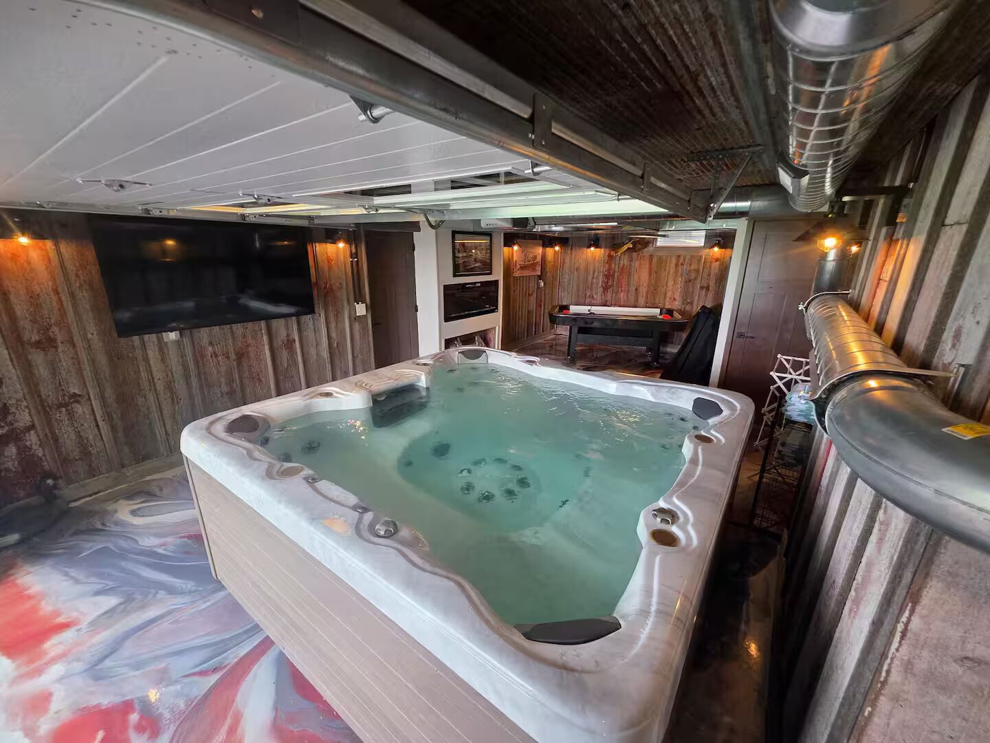 A hot tub in a room with wooden walls and a ceiling with exposed ductwork.