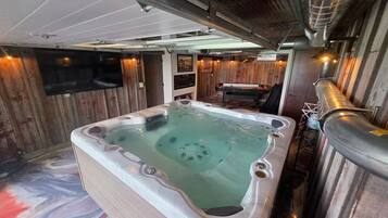 A hot tub in a room with wooden walls and a ceiling with exposed ductwork.