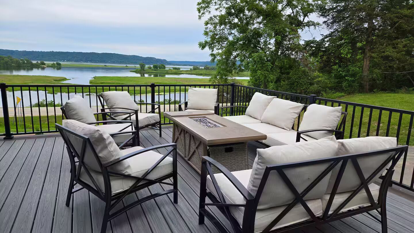 A deck with outdoor furniture and a view of a lake.