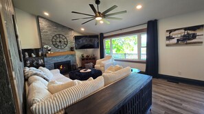 A modern living room with a fireplace, comfortable seating, a television, and a large window with a view. - Mississippi River view. Duck Hunters Get away. 4 Bedroom, 5 bed - Sleeps 10. (Brownsville)