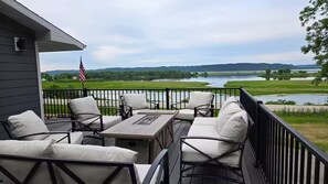 A deck with outdoor furniture, a flag, and a view of a lake and hills. - Mississippi River view. Duck Hunters Get away. 4 Bedroom, 5 bed - Sleeps 10. (Brownsville)