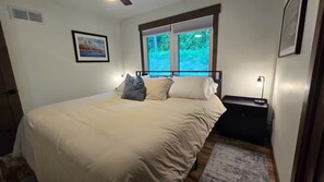 A bedroom with a bed, a nightstand, a window with blinds, and a framed picture on the wall. - Mississippi River view. Duck Hunters Get away. 4 Bedroom, 5 bed - Sleeps 10. (Brownsville)