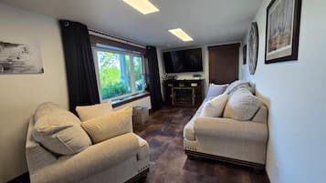 Un salon avec deux canapés, une cheminée et une grande fenêtre.
