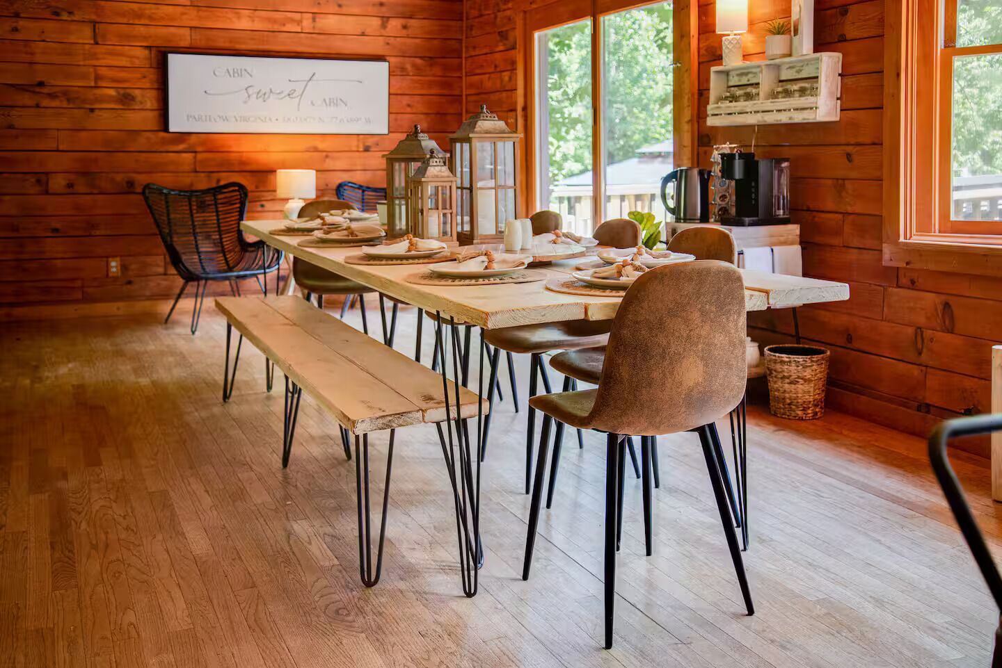 A wooden cabin interior with a dining table set for four, surrounded by chairs, and a bench.