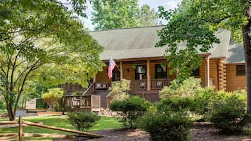 Un chalet avec une façade en bois, une véranda et un drapeau américain.