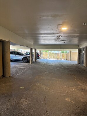 An indoor parking area with concrete pillars, a white ceiling, and a light fixture. - Condo near UT Austin, Capital. and freeways (Austin)