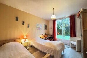 Habitación con dos camas, un escritorio, una silla y una ventana con vista a zonas verdes.