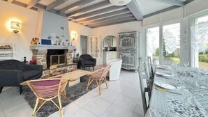 Ein geräumiges Wohnzimmer mit Kamin, Sitzecke und großen Fenstern.