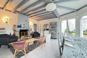 A spacious living room with a fireplace, seating area, and large windows. - Les Sylphes - Parking, WiFi, TV, 350m to the beach (Pornichet)